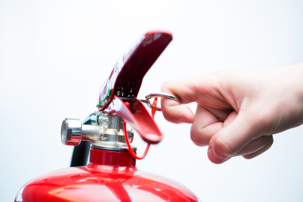 Hand pulling pin of fire extinguisher